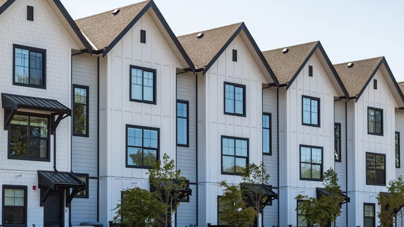 Row of three-story townhomes with gabled asphalt shingle roofs