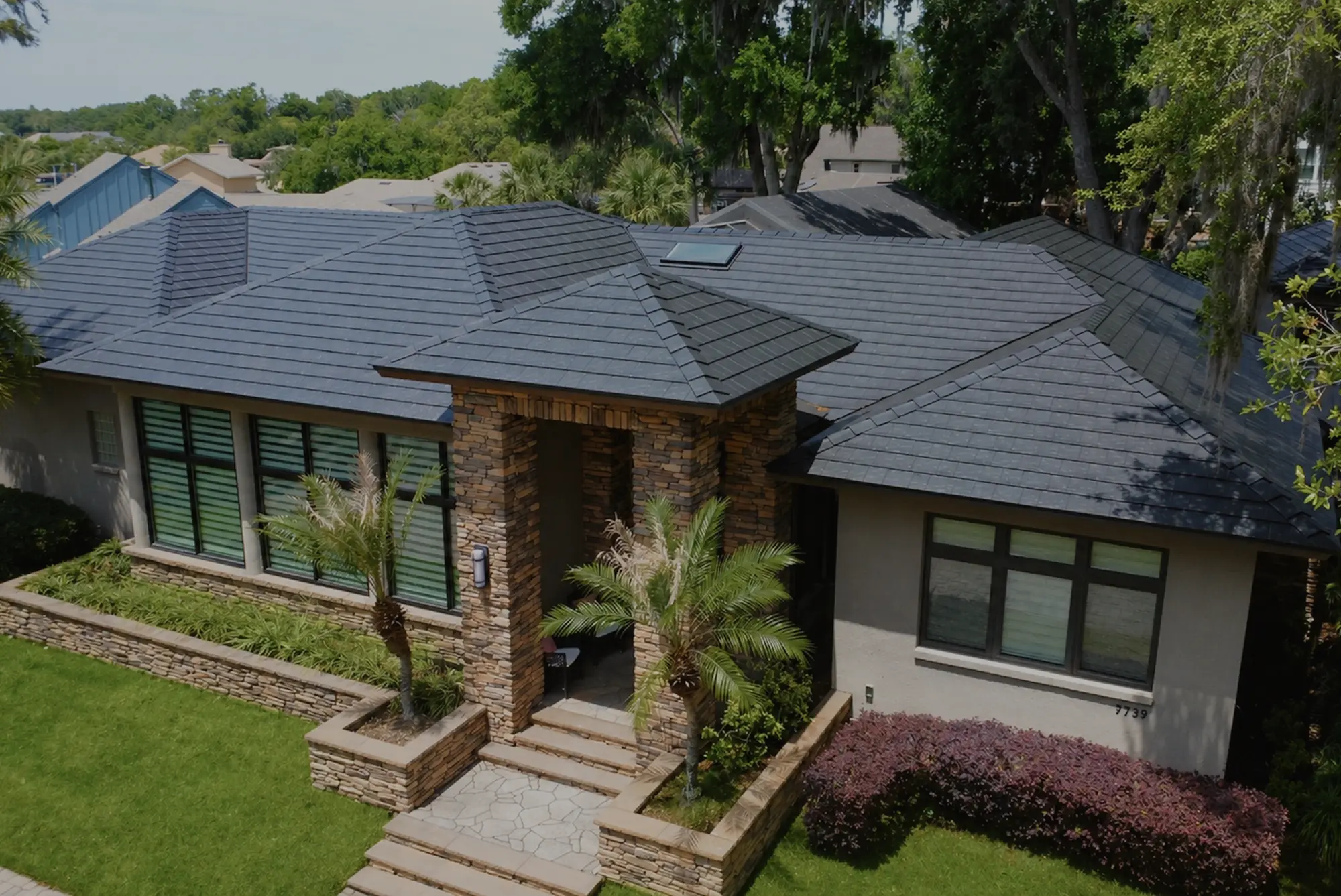 Metlok pressed-steel slate-profile roof on a premium Florida stone-and-stucco home