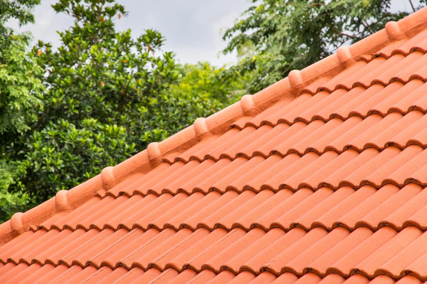 Low-angle view of a terracotta barrel tile roof against green Florida oaks in Orlando