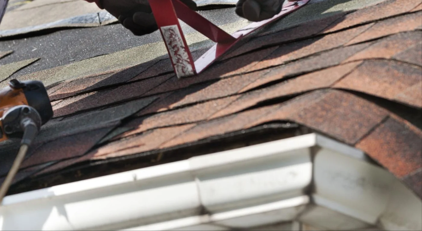 Image of someone in gloves working on an asphalt roof