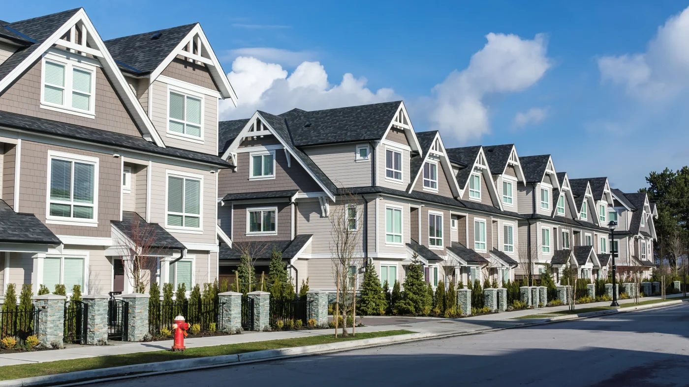 A row of multi-family housing with asphalt shingle roofing