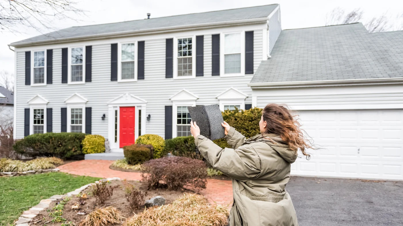 A homeowner holds shingles blown off during a storm
