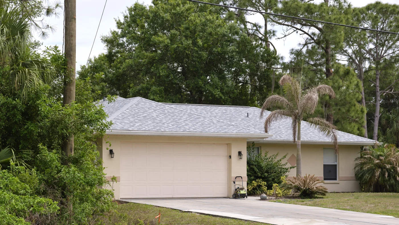 Front view of regal two-story home with white exterior and black metal roof