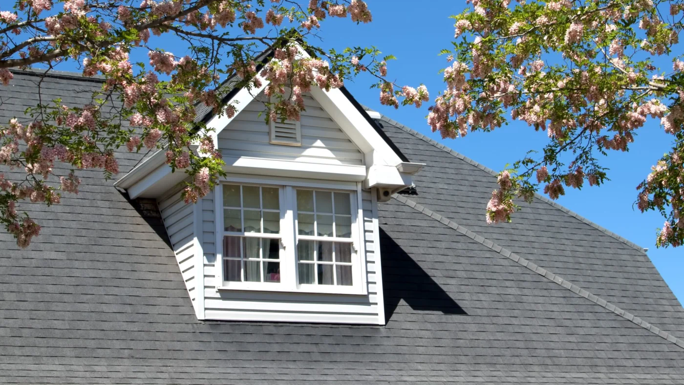 House With A Dormer In Its Roof Stands Beneath A Clear Blue Sky On A Sunny Day House With A Dormer In Its Roof Stands Beneath A Clear Blue Sky On A Sunny Day