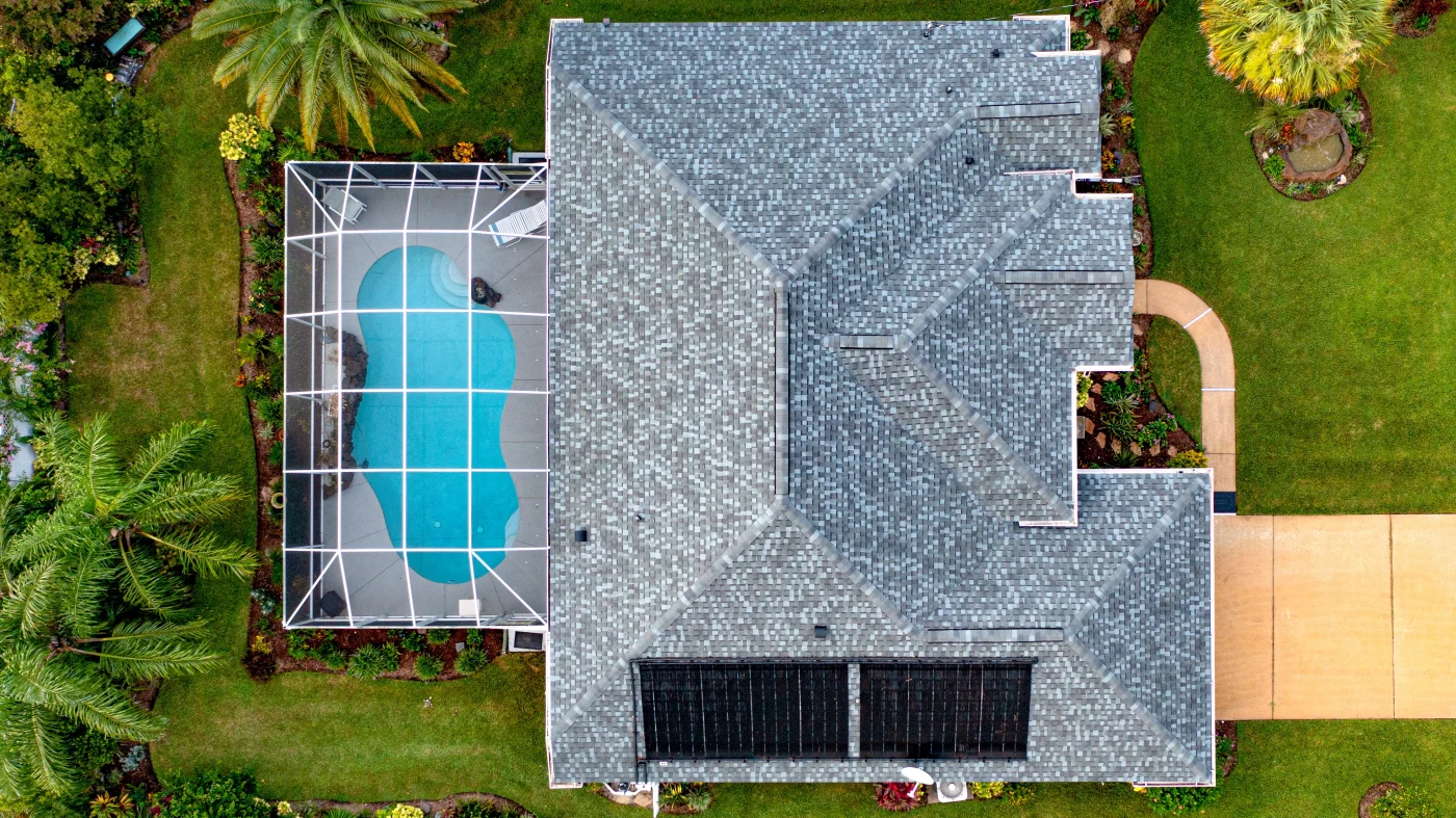 Drone view of a home with a new asphalt shingle roof and impeccable yard
