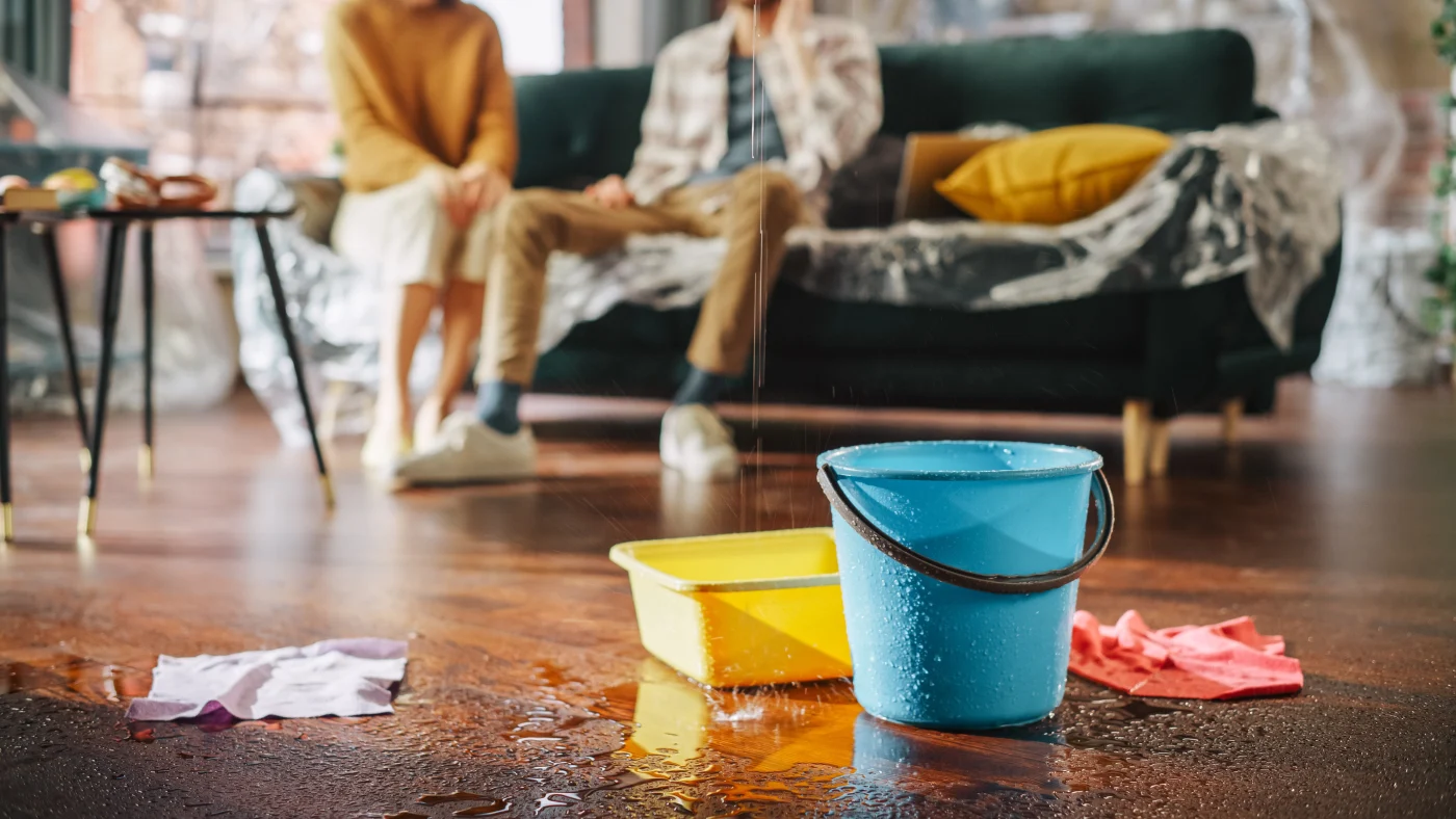 Buckets catching water from a roof leak in a living room