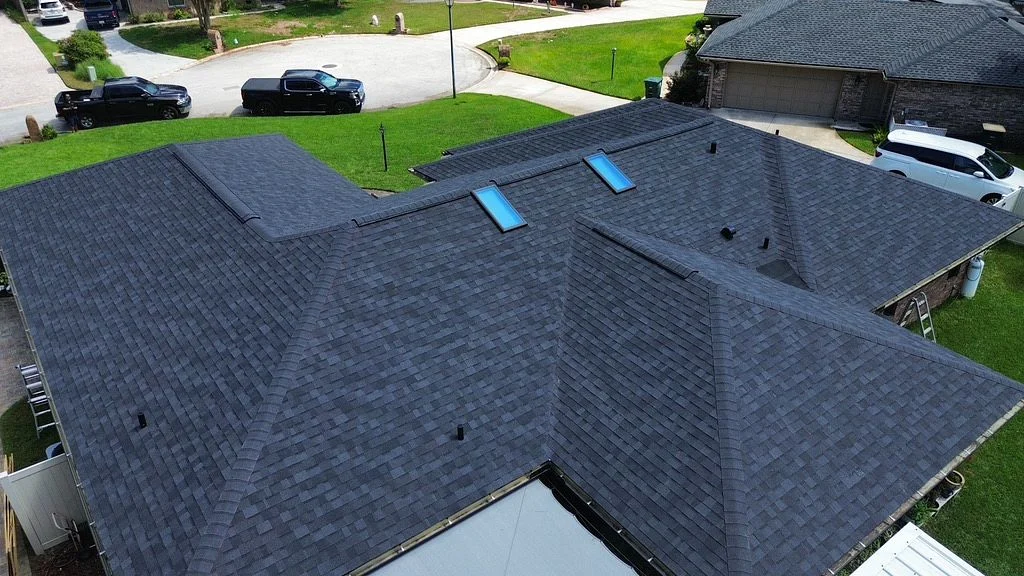 Aerial view of a large asphalt shingle roof on a house with a pool