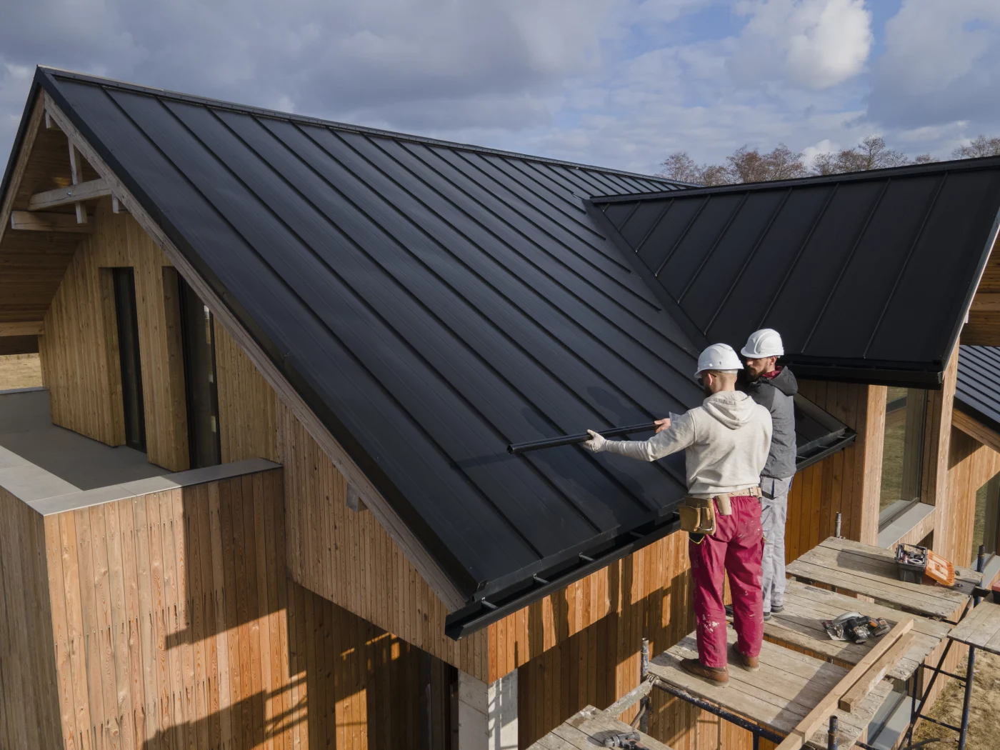 Expert roofers installing metal roofing on a large house