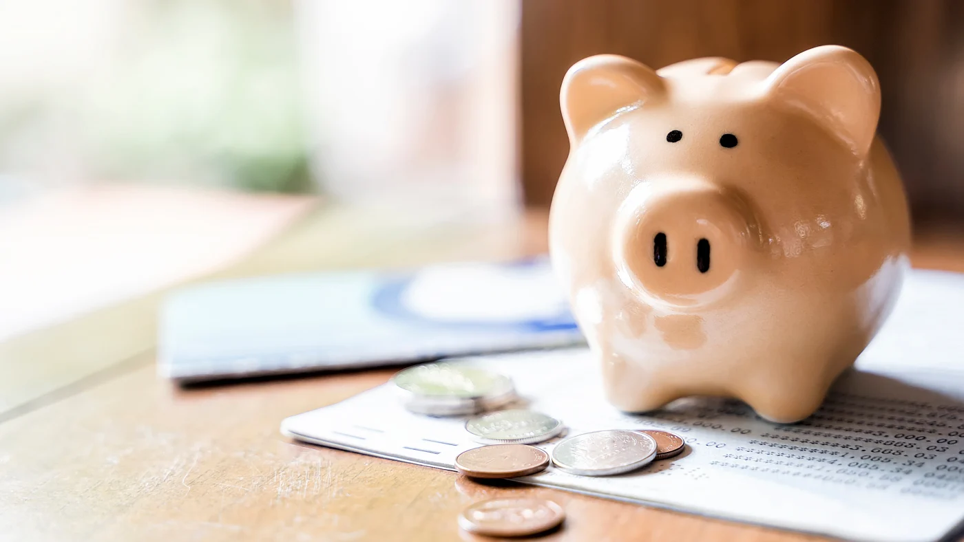 Financing | Central Florida | Universal Roof & Contracting Pink piggy bank sitting next to coins in Central Florida | Universal Roof & Contracting