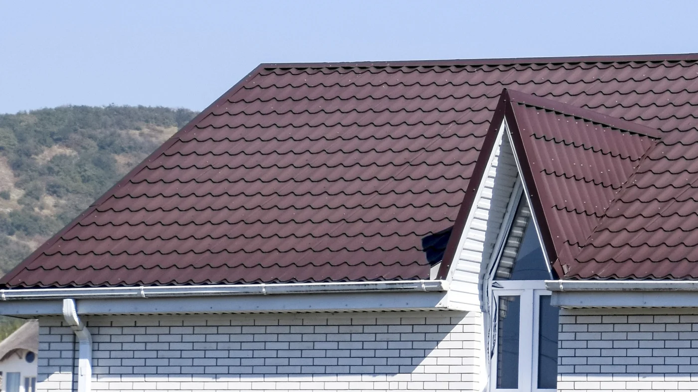 Home with dark red metal roofing with a sky view in the background