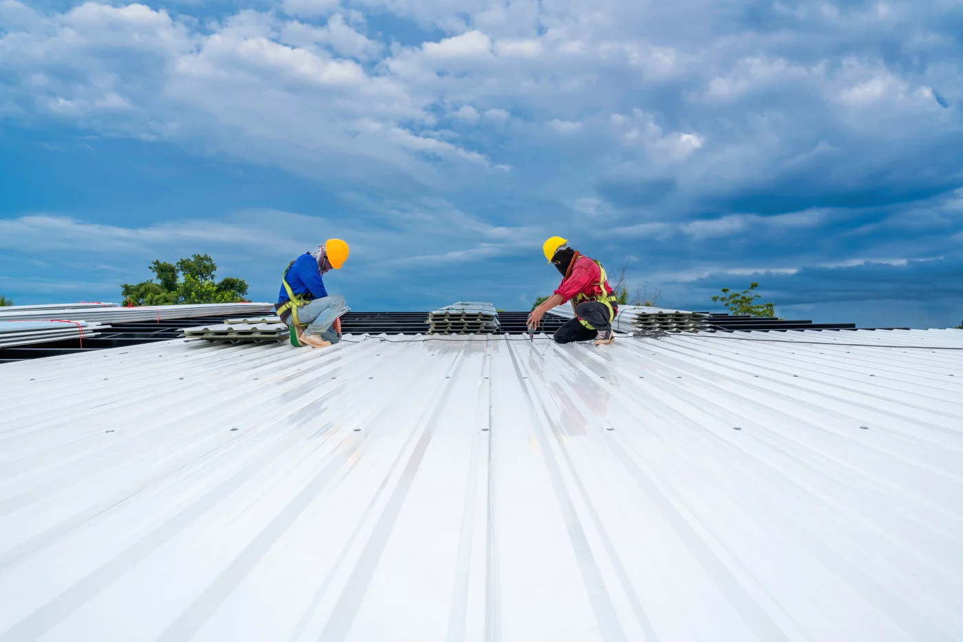 Two Universal Roof & Contracting contractors working on the metal roof of a Jacksonville, FL commercial property.