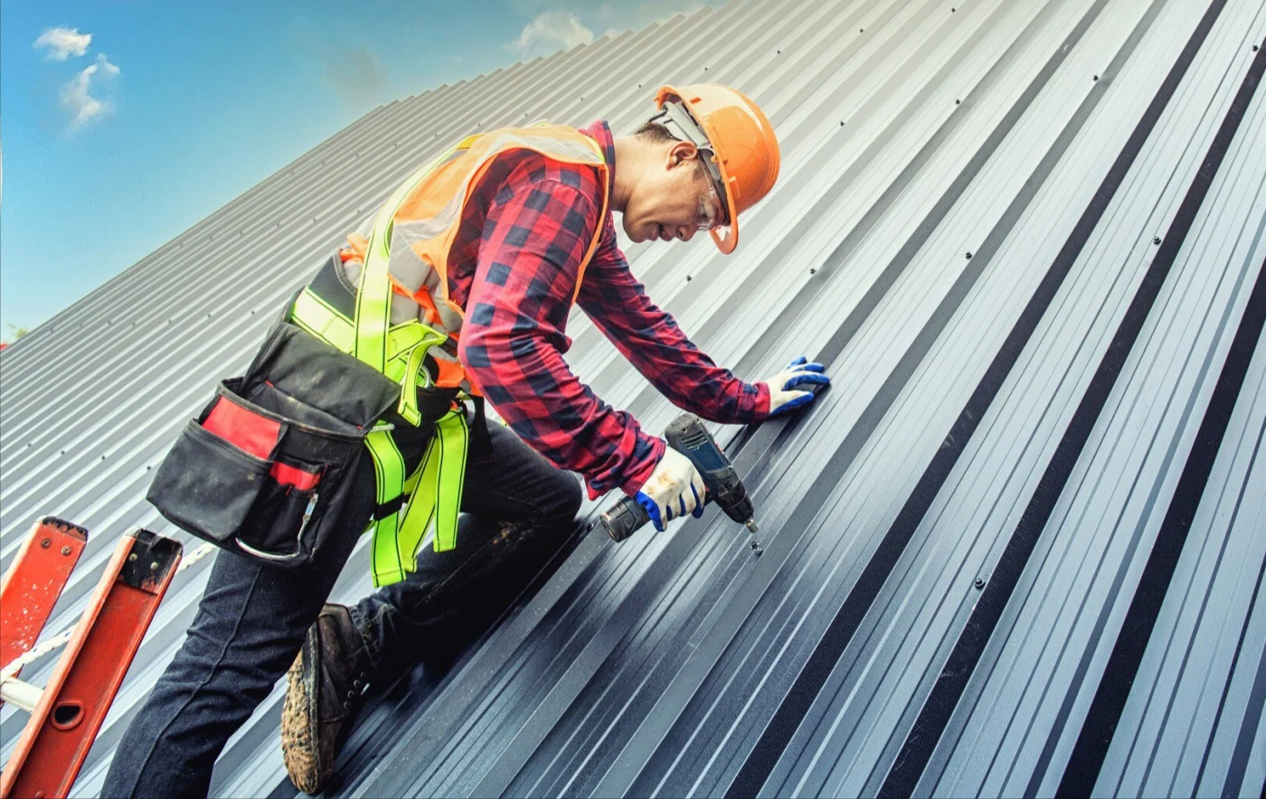 Image of a man in safety gear working to install a metal roof