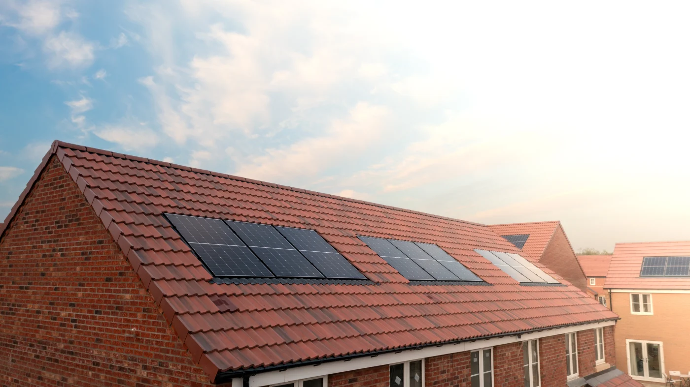 A brick home with terra cotta colored roofing with solar panels