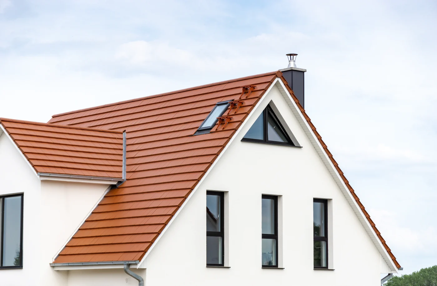 Residential Roofing | Poinciana | Universal Roof & Contracting Top of rust colored metal style roof on a stucco white home