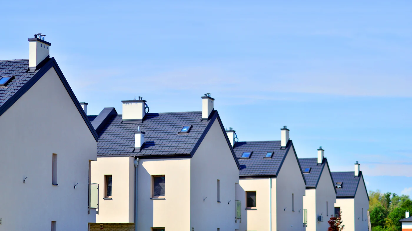 Sand colored row houses with metal roofs against a light blue sky