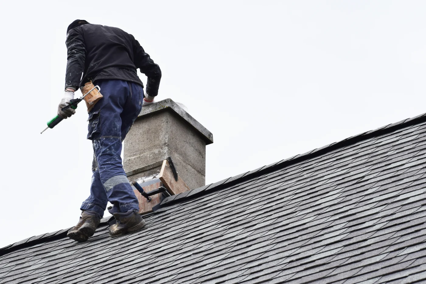 Professional residential roofer repairing a chimney and flashing