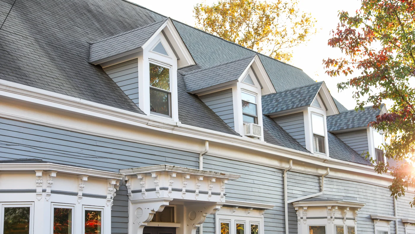 Aerial view of large home with dark stone siding and asphalt roofing
