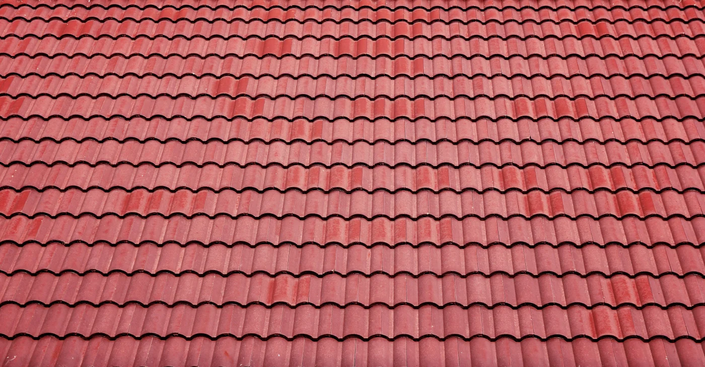 A close-up of a textured, wave-like, red, Spanish-style tile roof