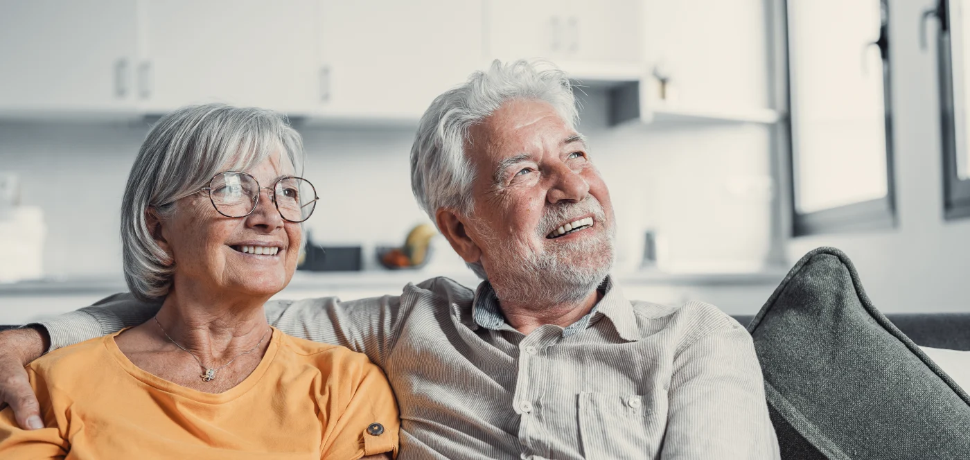 An older adult couple sitting happily in their home
