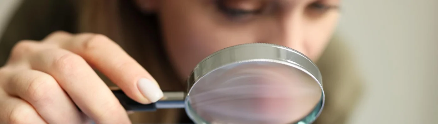 A woman staring through a magnifying glass