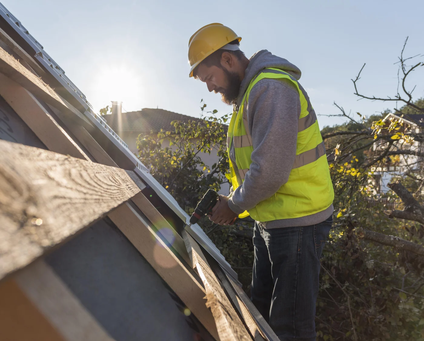 Image of a man working on a roof with a drill
