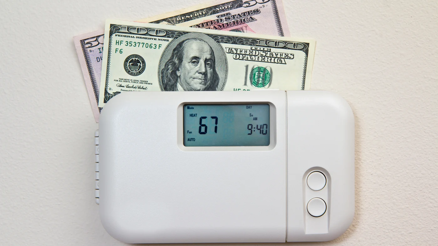 A thermostat with $150 resting behind it