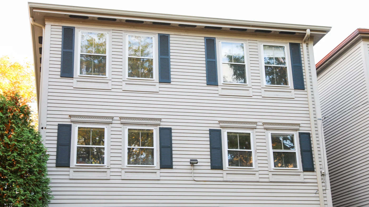 Two-story home with four windows and off-white colored siding