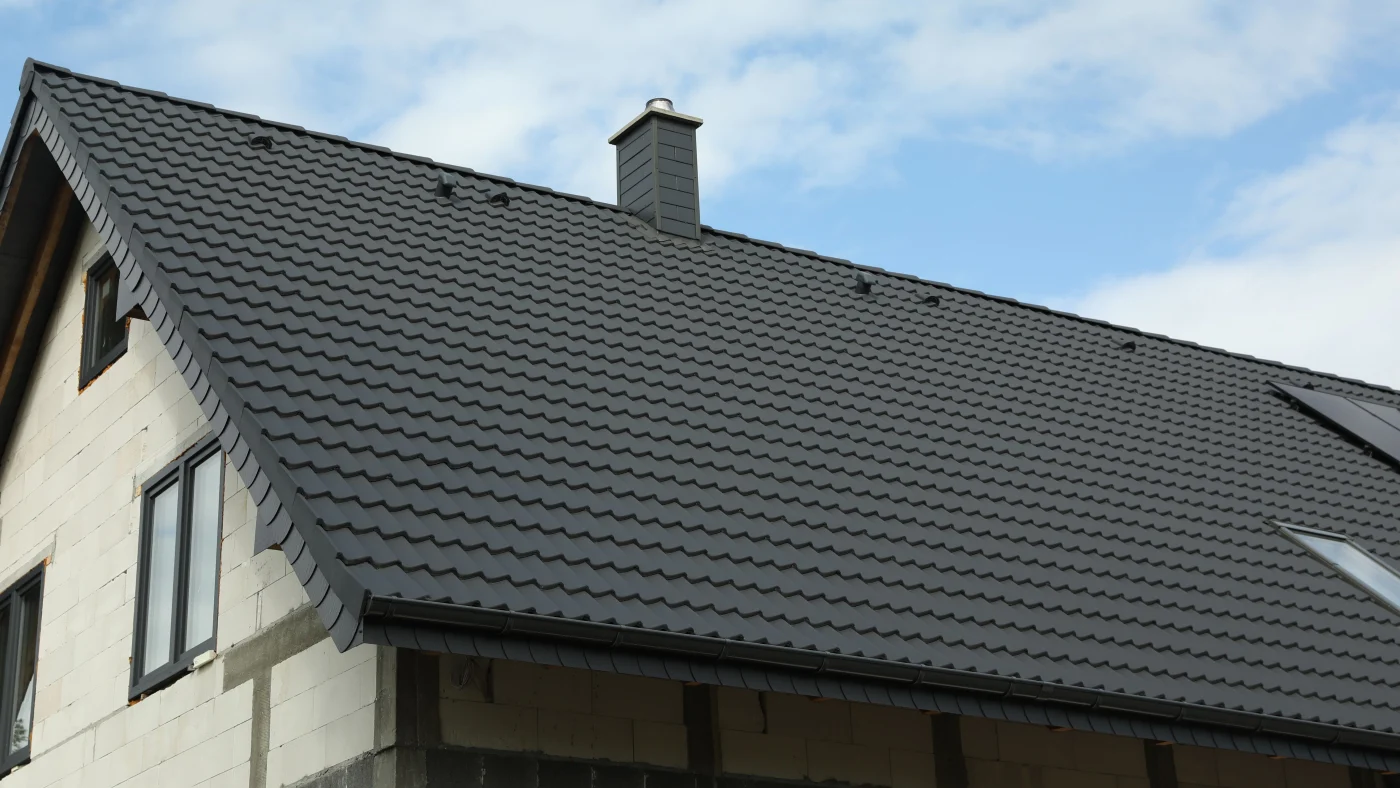 Large new dark metal roof on home with white brick siding