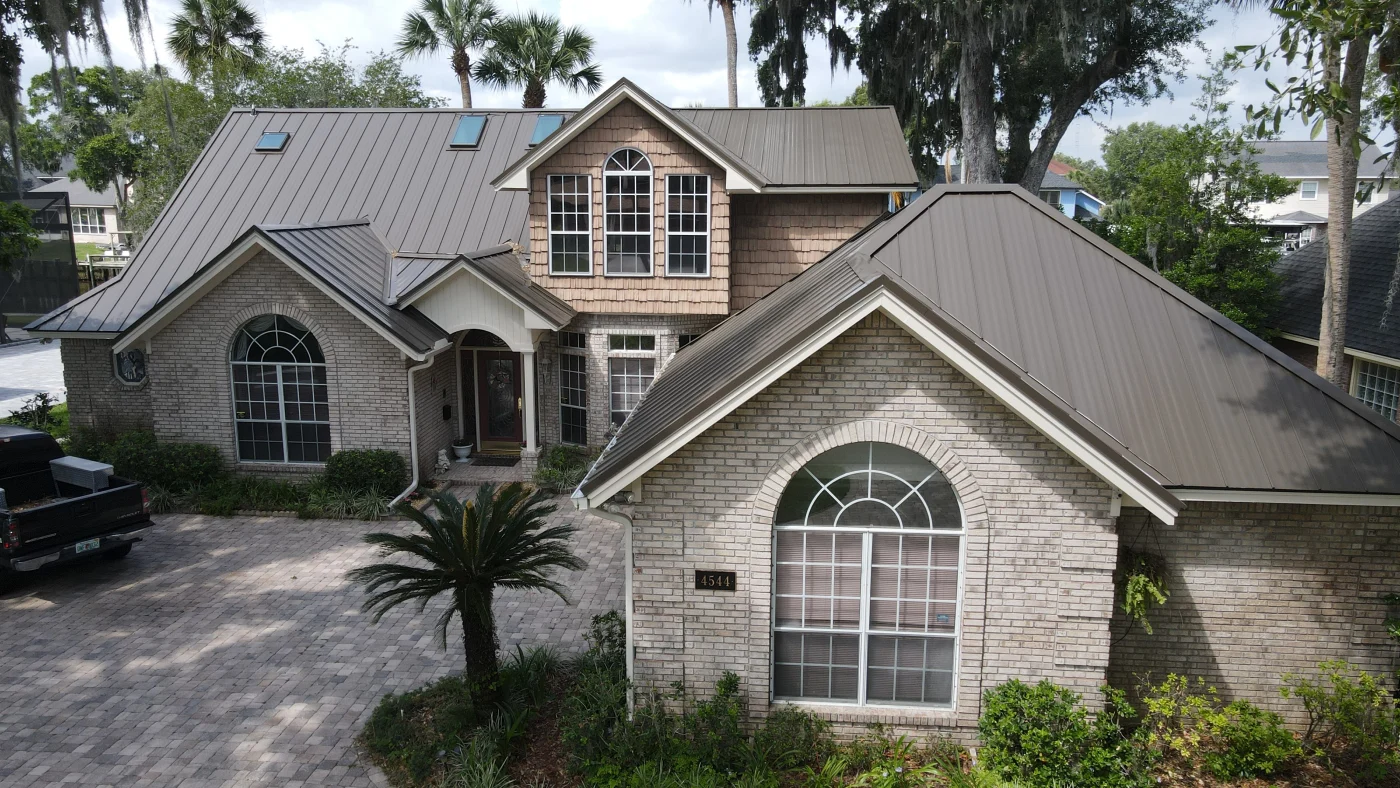 A home with a standalone building with new gray metal roofs