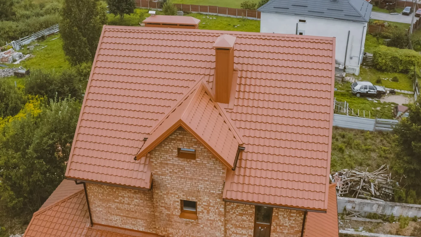 Aerial view of home with large orange tile roof and brick siding