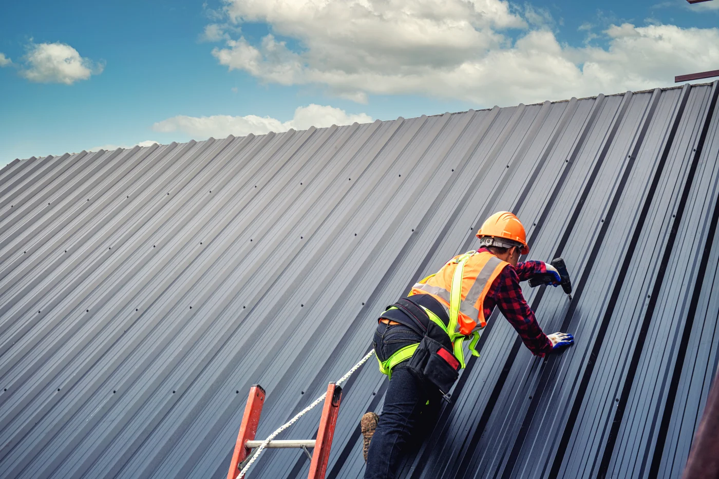 A roofer works on a commercial metal roof.