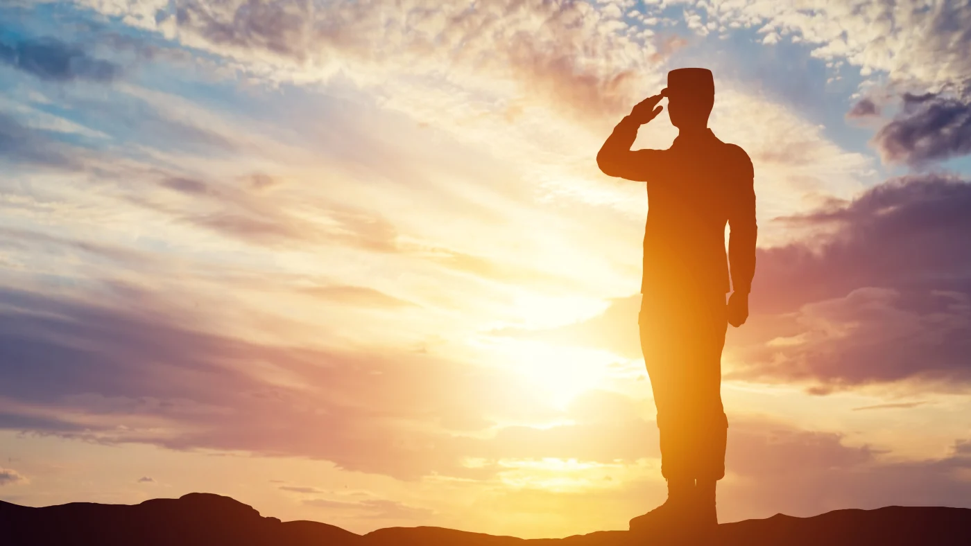 Veteran-Owned Roofing Company | Universal Roof & Contracting A soldier stands at attention, silhouetted by the sun in Central Florida | Universal Roof & Contracting
