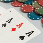 Four of a kind aces laid out on a table in front of many poker chips.