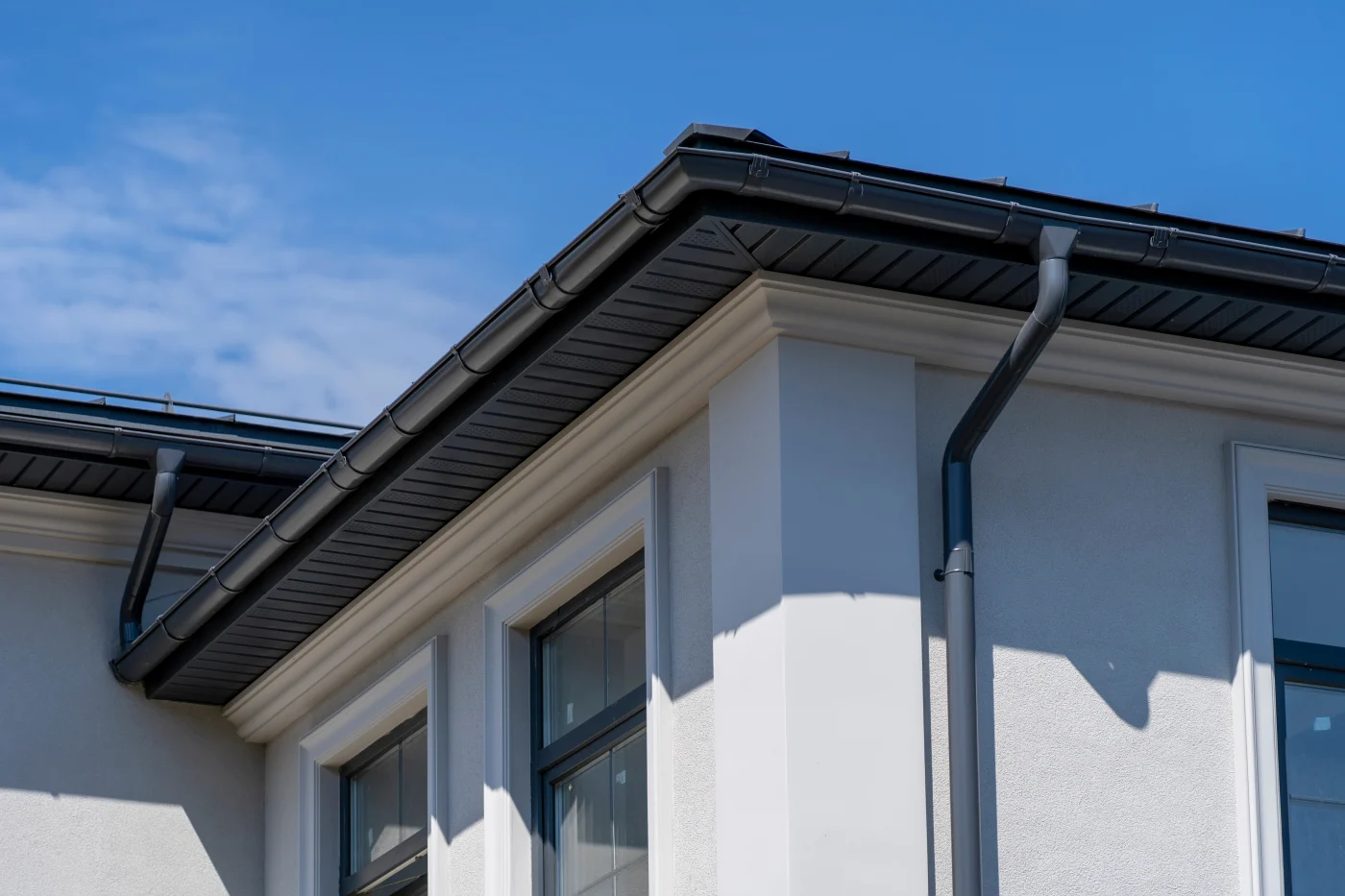 Black soffit and fascia wrapped around a white stucco house with black gutters.