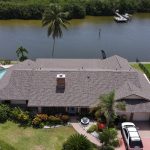 An aerial view of a large, dark brown, architectural asphalt shingle roof on top of a FL home next to a canal