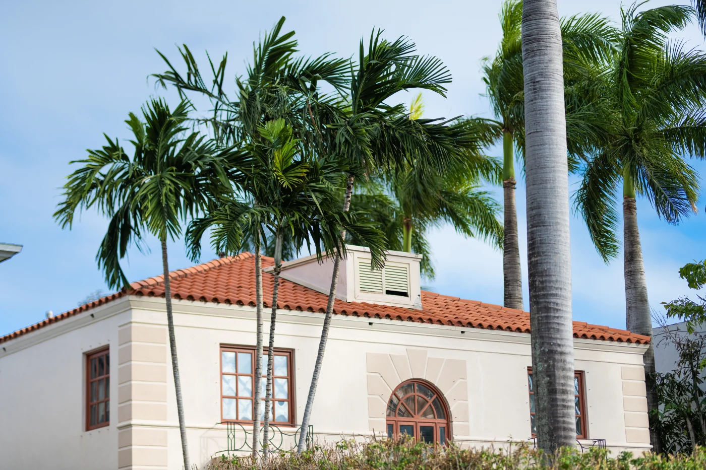 Apartment Building With Entrance. House Building In Neighborhood. Residential Building Architecture. Architectural Exterior Style. Residential House Exterior. Modern Apartment Building. Palm Tree A Spanish inspired home with a red tile roof surrounded by palm trees.