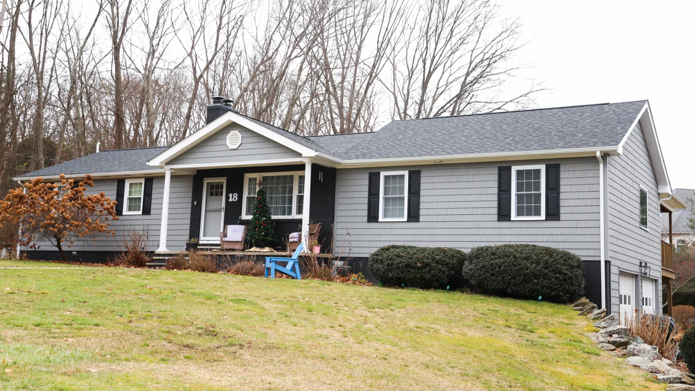 A wide home with gray siding and a dark asphalt shingle roof.