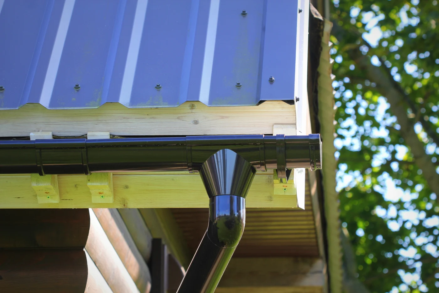 A close-up view of newly-installed gutters and a downspout on a house.