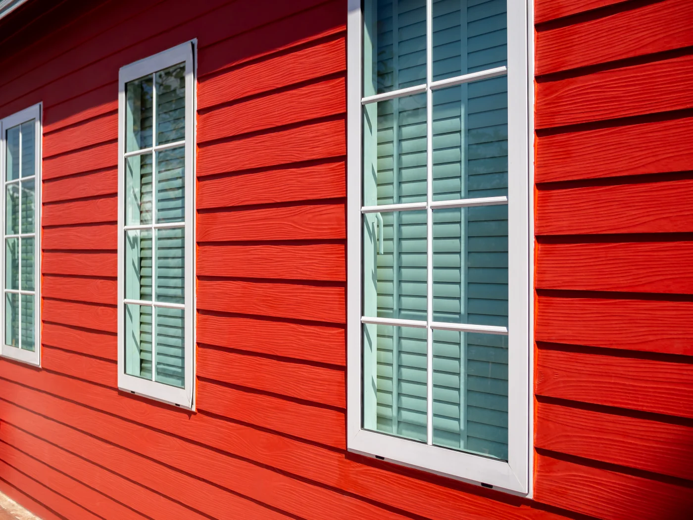 A close-up view of orange siding on a house with white windows.