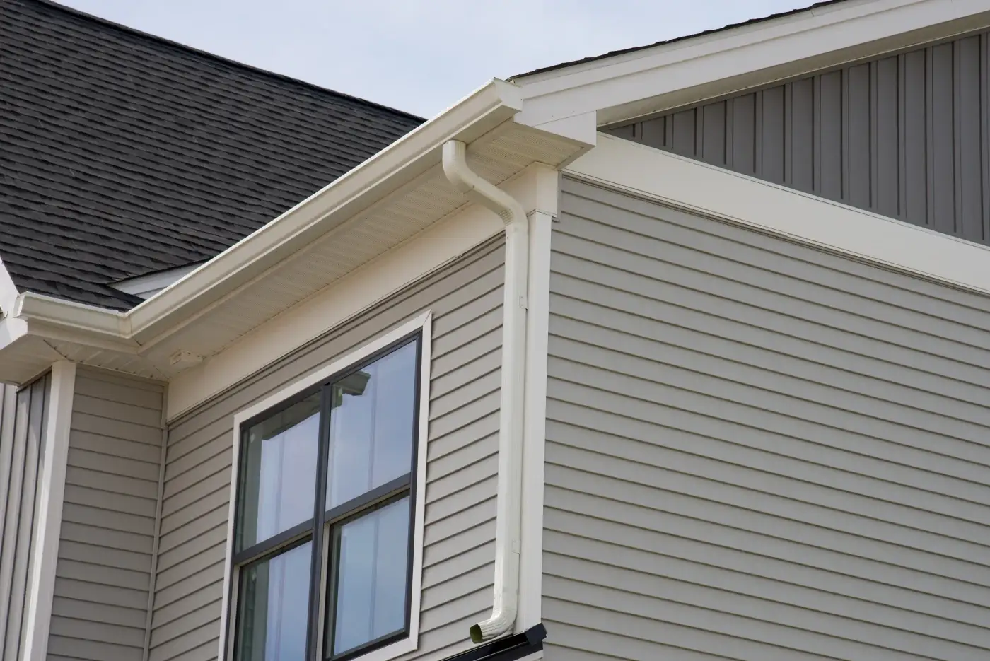 Home with gray siding, white soffits and fascia, and white gutters installed.