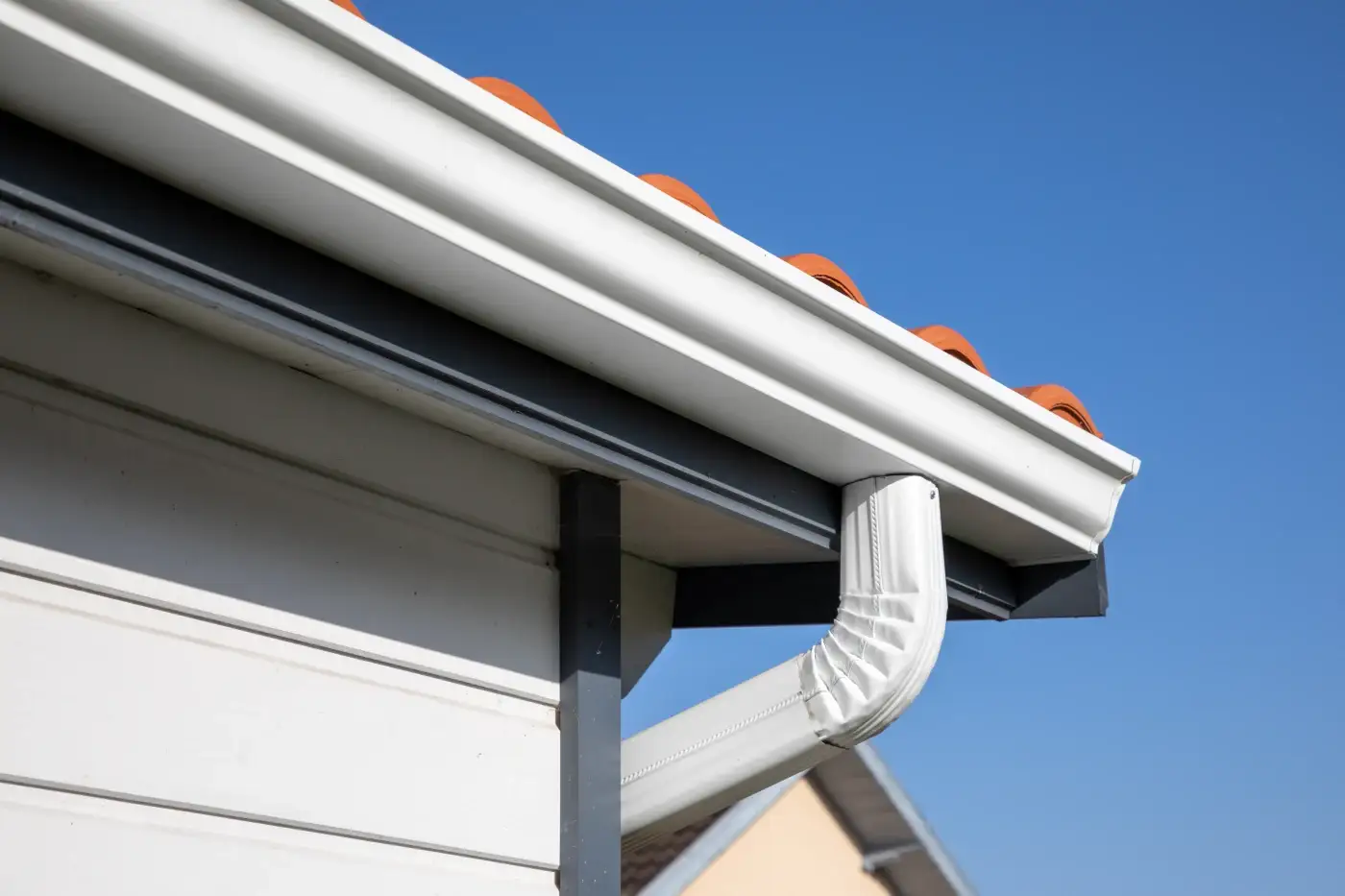 The corner of a house with gray soffit and gutters.