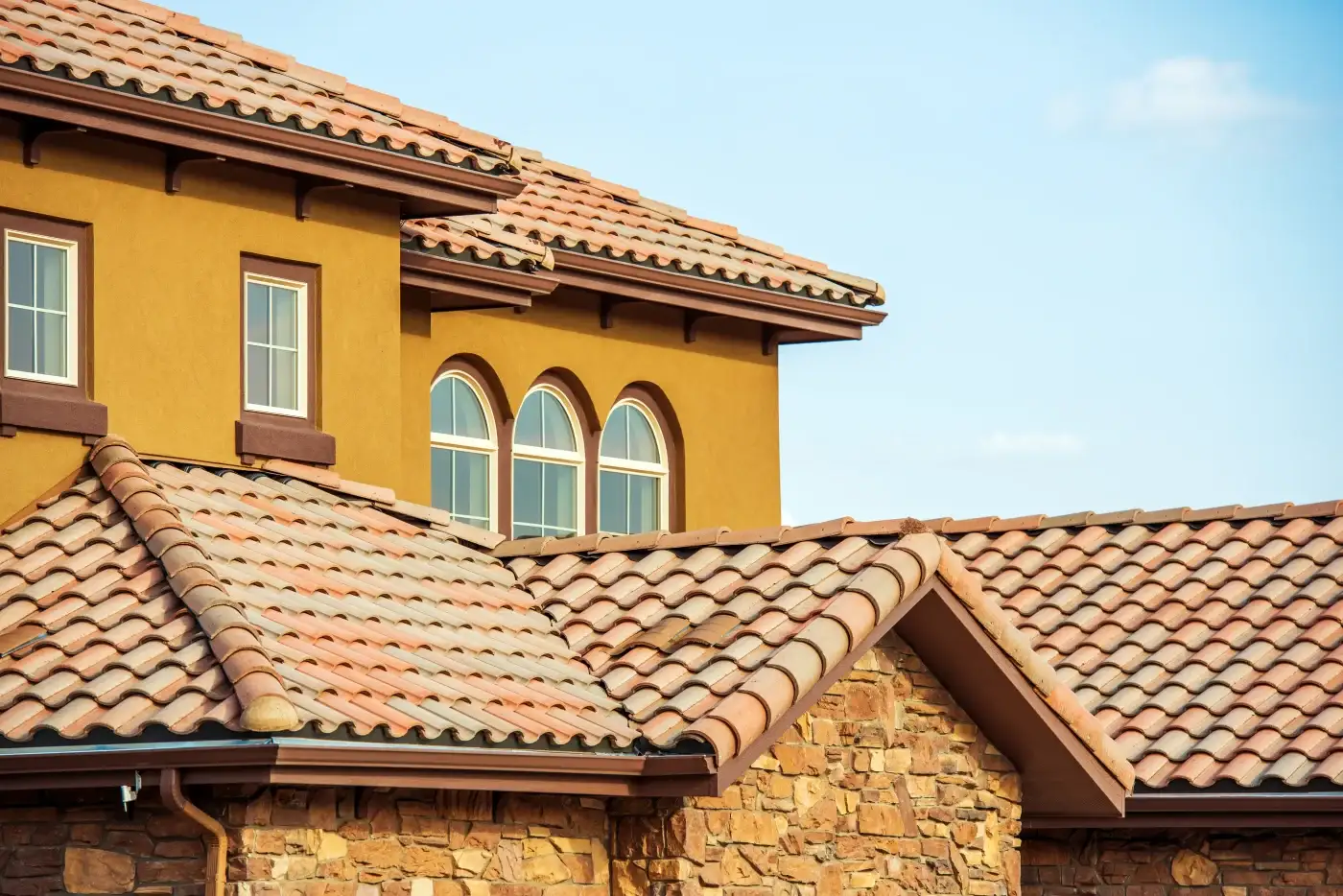 A close up view of a red tile roof installed on a two-story home.