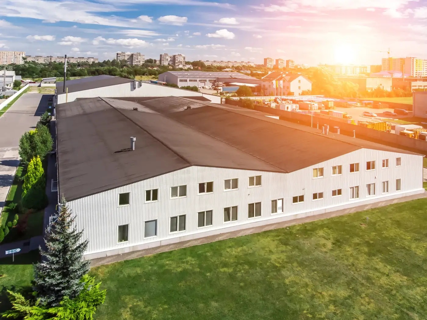 The roof of an apartment complex with white stucco siding and a red tile roof under a blue sky.