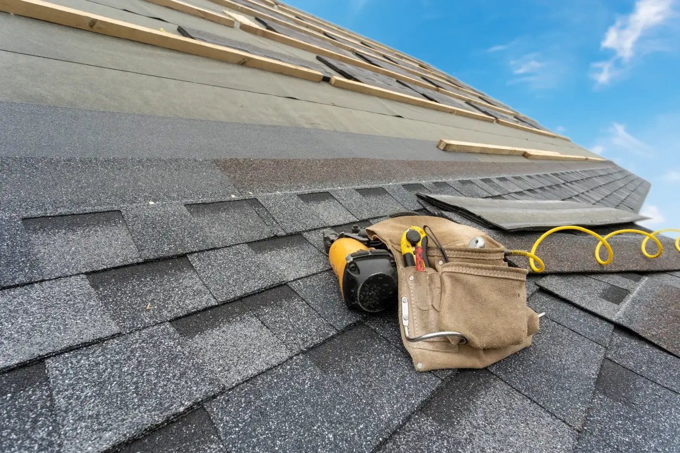 Roofer repairing brown asphalt shingle roof on a Palm Coast, FL home.
