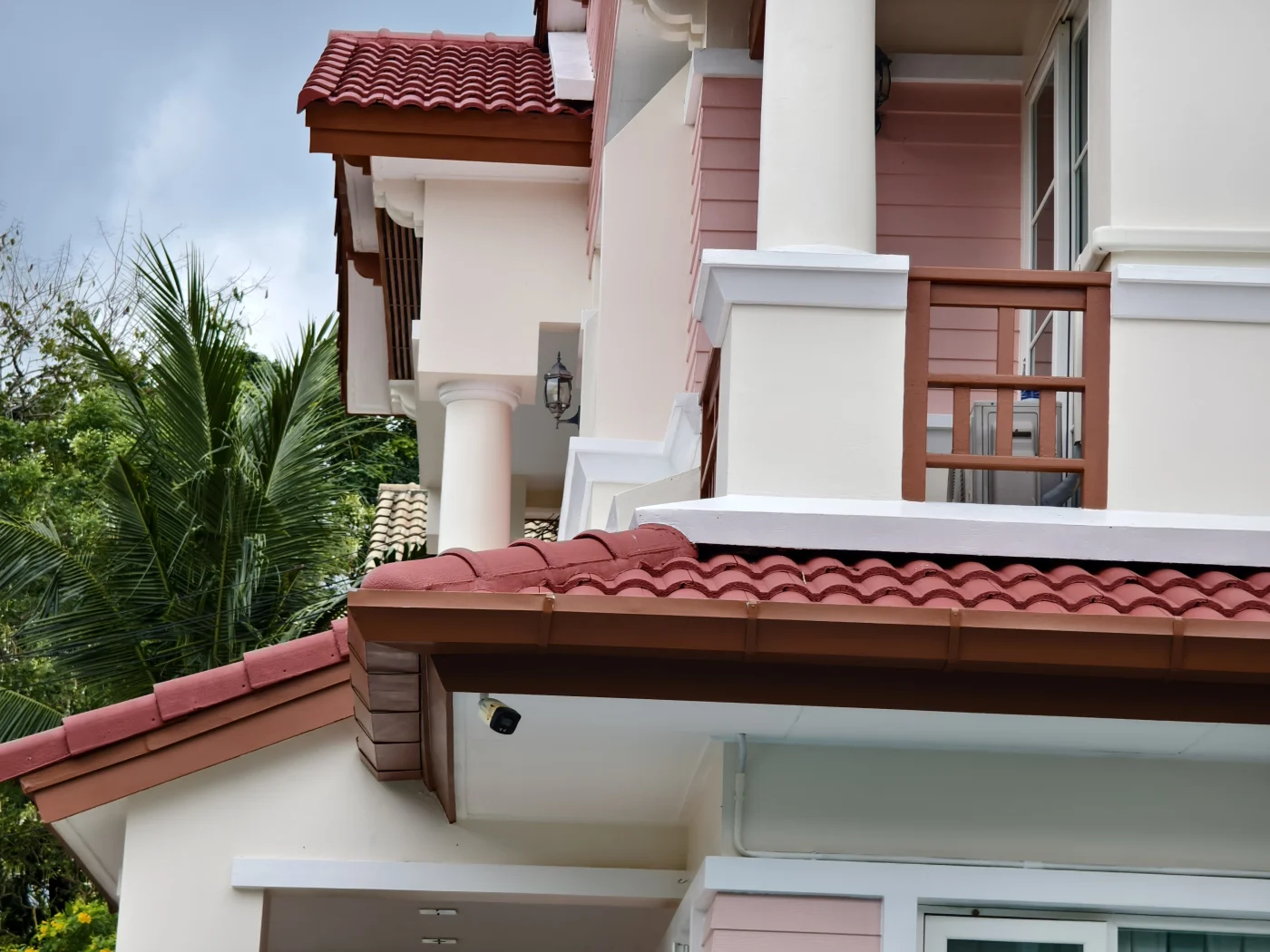Gorgeous Tile Roof | Bradenton, FL | Universal Roof and Contracting Close-up view of a multi-level home featuring red curved tile roofing, cream exterior walls, white columns, and brown trim accents.