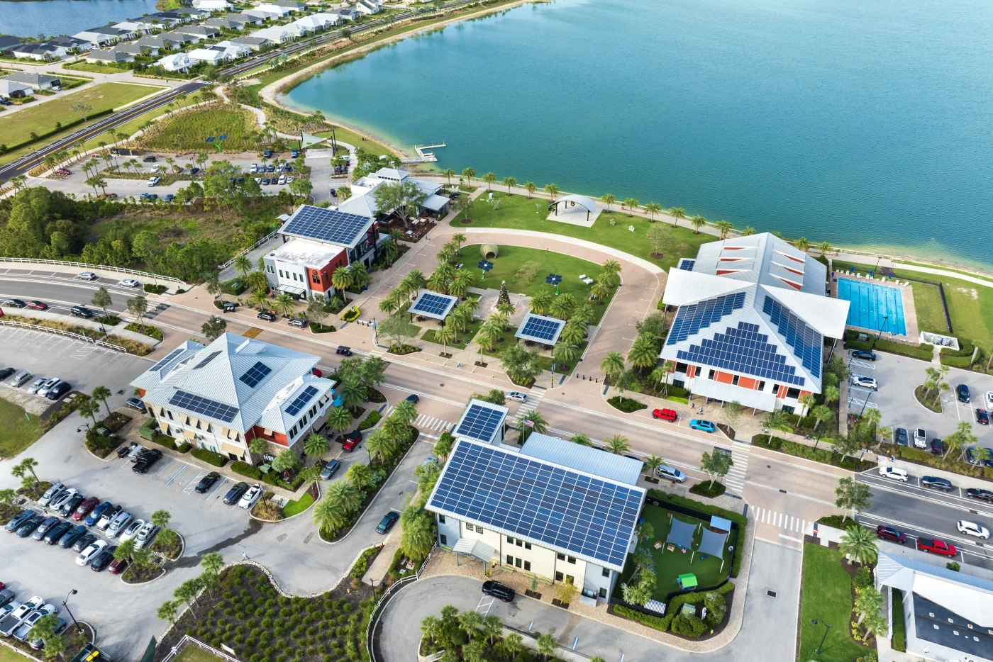 Outstanding Commercial Roofing | Macclenny, FL | Universal Roof and Contracting Aerial view of a waterfront commercial district featuring multiple modern buildings with large solar panel arrays on metal roofs.