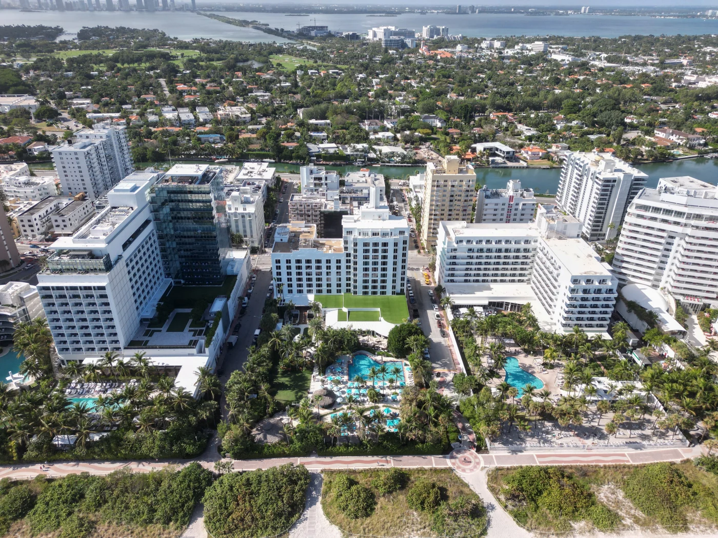 Stupendous Commercial Roofing | Riverview, FL | Universal Roof and Contracting Aerial view of a coastal cityscape featuring multiple high-rise hotels, resort pools, palm trees, and landscaped walkways along the beachfront, with waterways and distant buildings visible in the background.