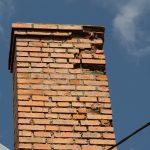 Close-up of a weathered brick chimney with visible cracks and deterioration, representing the type of chimney damage Universal Roof & Contracting repairs across Central Florida.