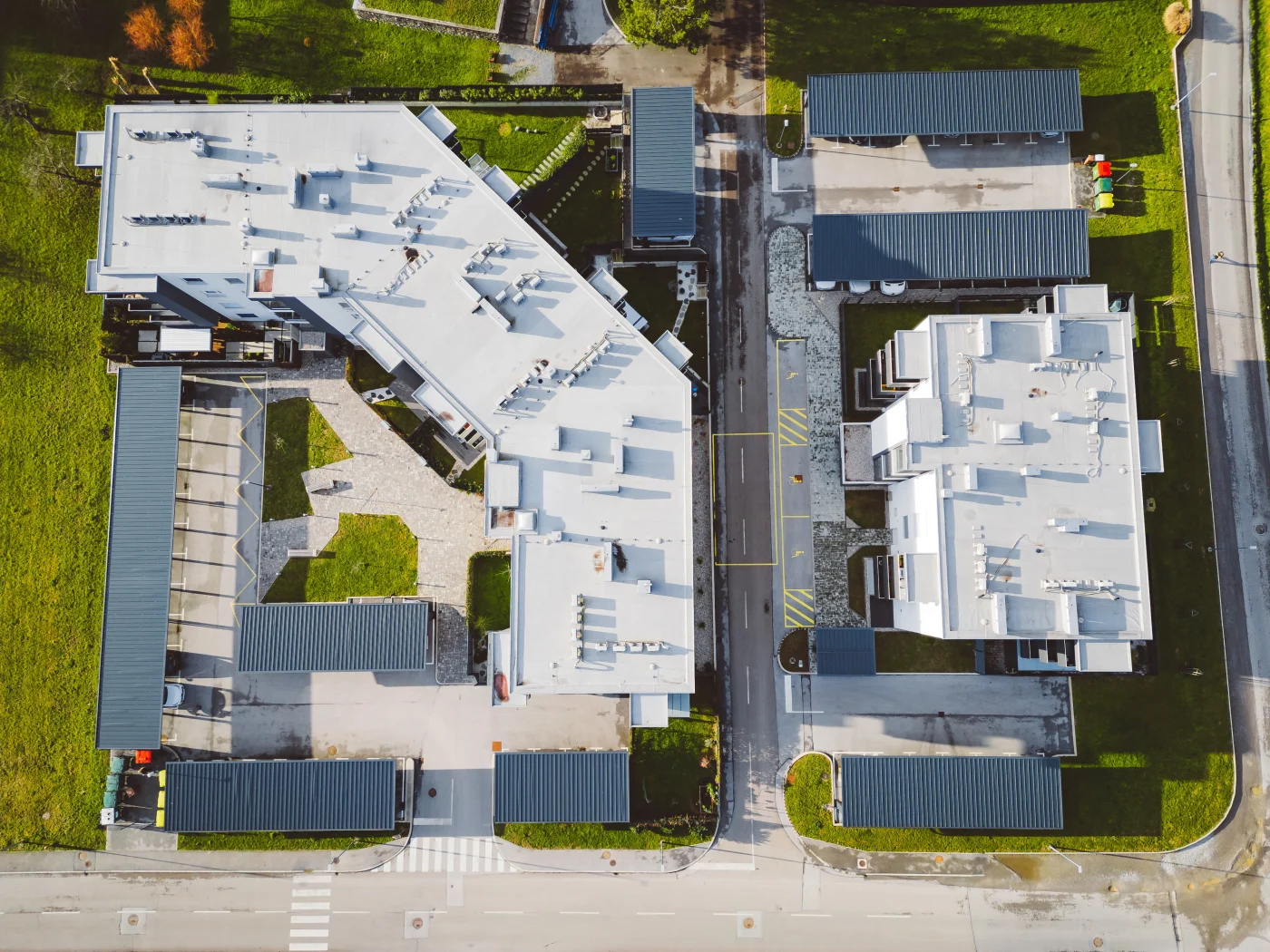 Flawless Commercial Roofing | Windermere, FL | Universal Roof & Contracting Aerial view of large commercial buildings featuring expansive white flat roofing systems, surrounded by parking areas and green landscaping.