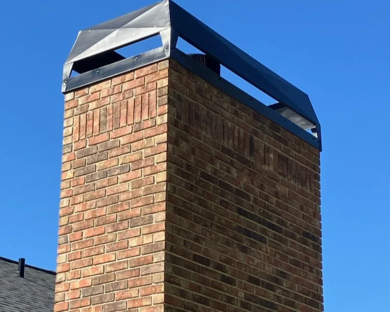 Close-up of a large brick chimney fully restored by Universal Roof & Contracting, featuring precise masonry detail and a new metal chimney cap against a clear blue Central Florida sky